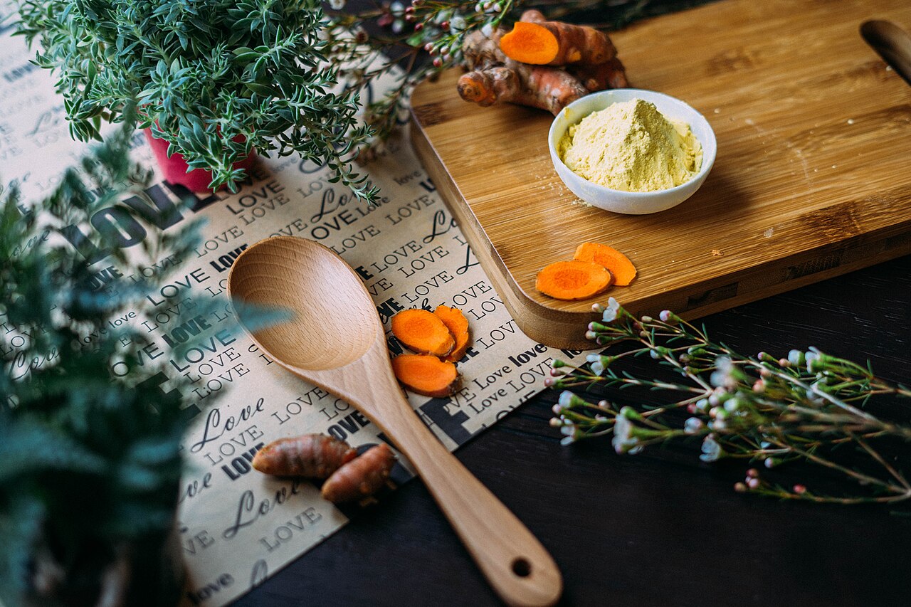 Fresh turmeric, herbs, and Thai medicinal spices on a wooden board